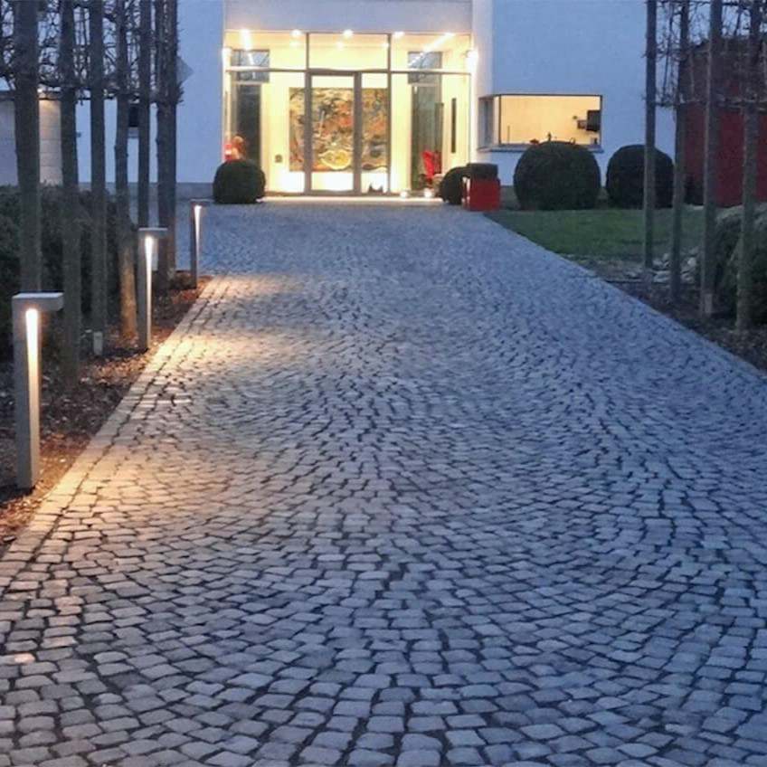 Fan-pattern black basalt cobblestone driveway lit at night