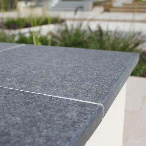 Close-up of flamed black basalt coping on a raised planter edge