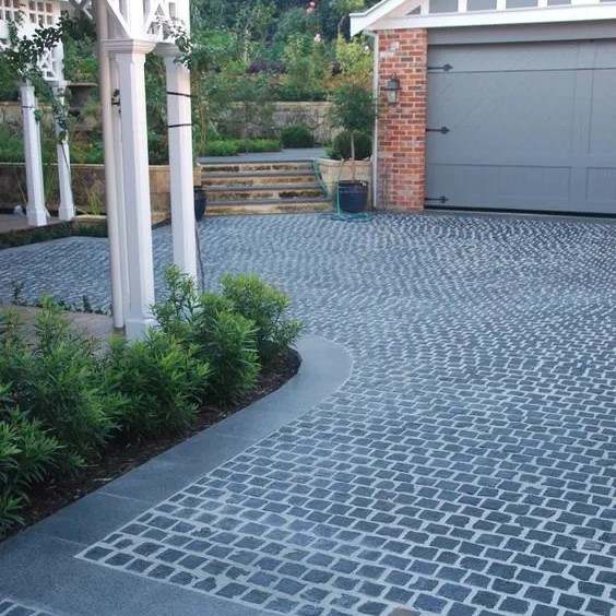 Black basalt cobblestone driveway with a smooth-edged border outside a garage
