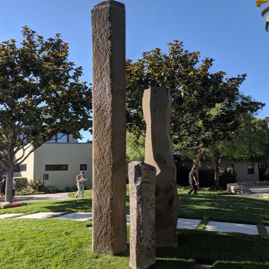 Tall standing basalt monoliths placed as garden sculptures on a lawn