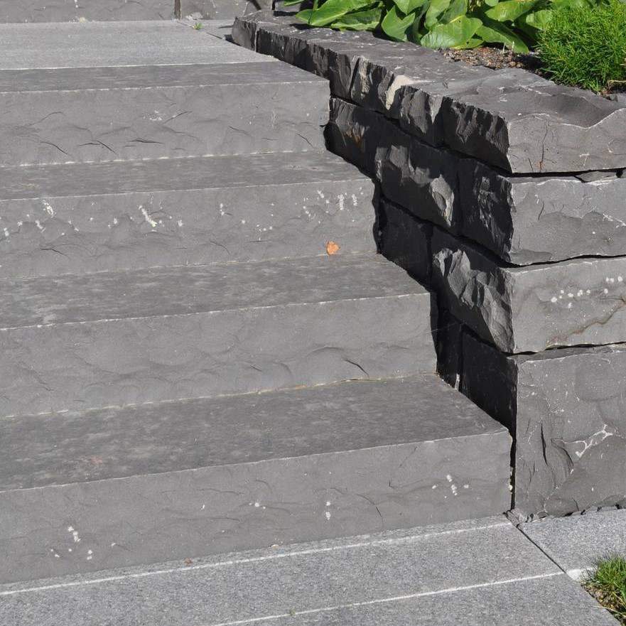 Black basalt steps with split-face nosing next to stacked stone